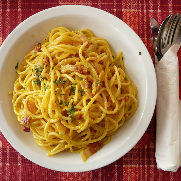 carbonara dish on a table with fork and spoon
