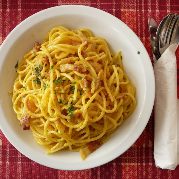 piatto di carbonara su un tavolo con forchetta e cucchiaio